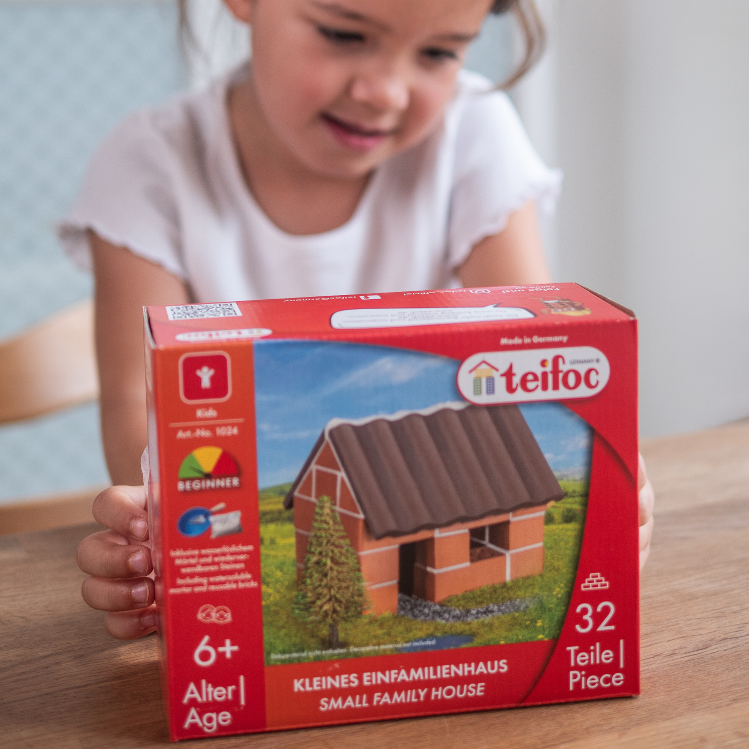 Mädchen betrachtet fasziniert die Verpackung des kleinen Einfamilienhauses