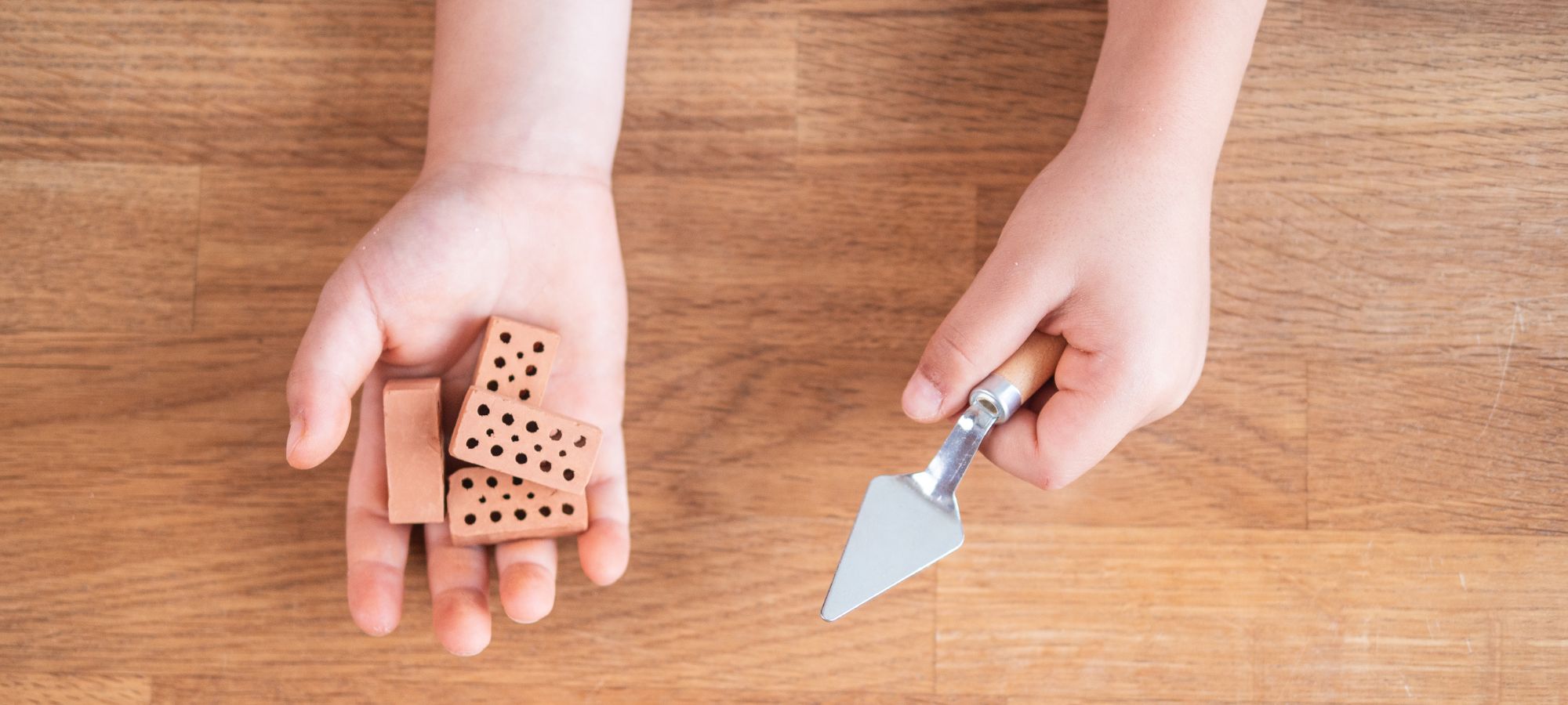 Kinderhände mit teifoc Mini Ziegelsteinen und Mini Maurerkelle